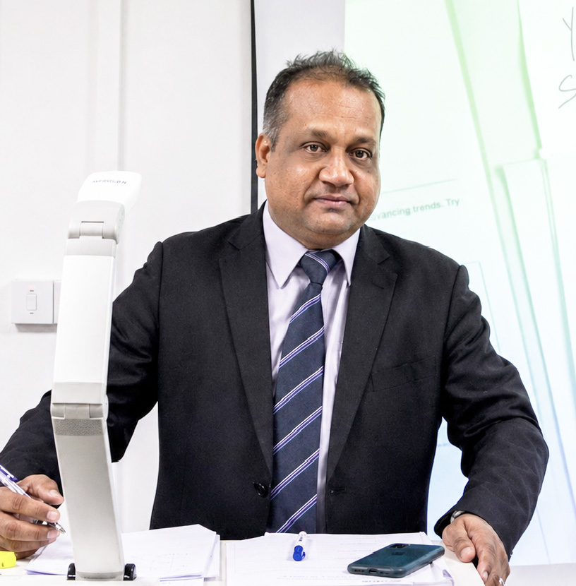 Mr Sham Mathura lecturing at a desk with a visualiser
